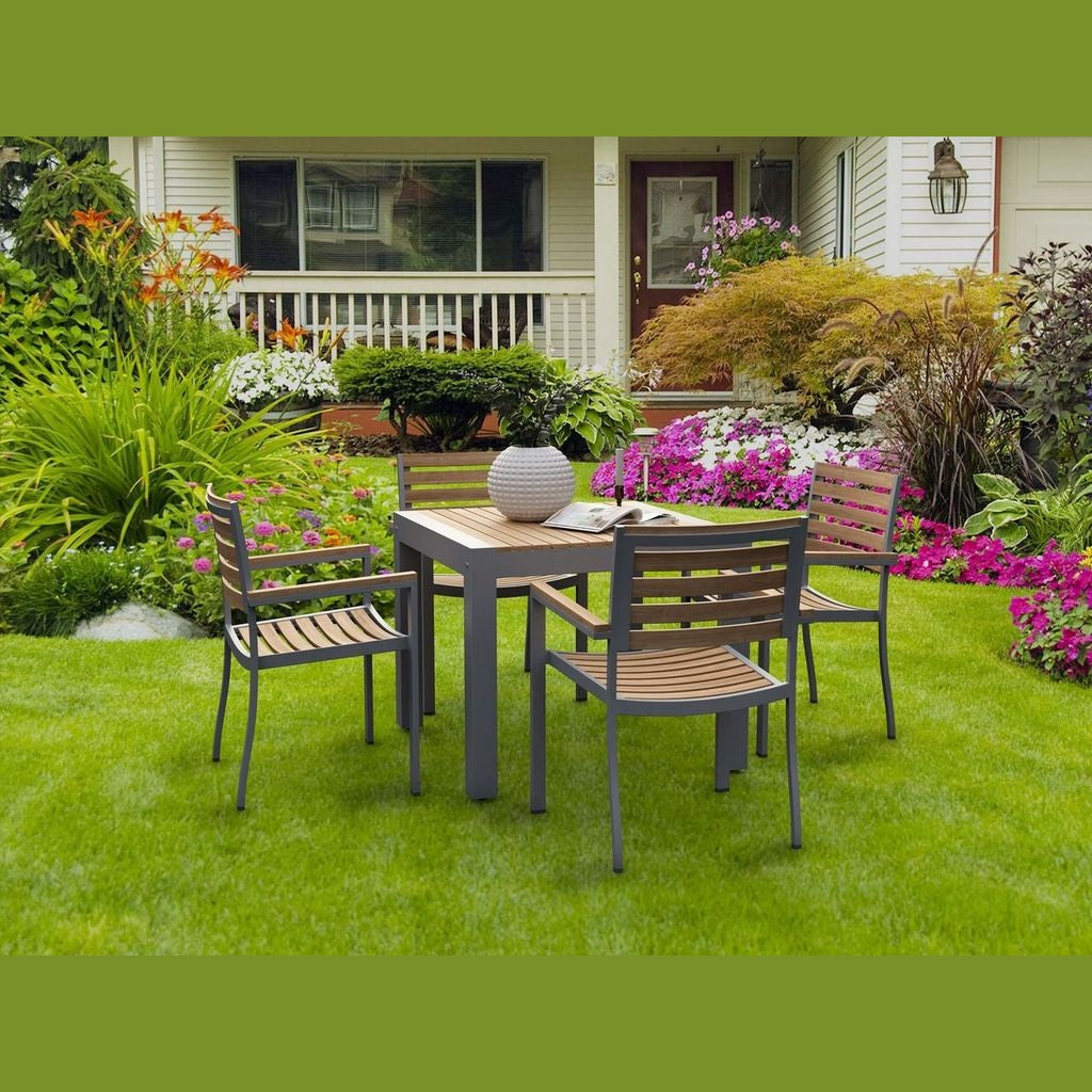 Outdoor patio set with table and chairs on a grassy lawn in front of a house.