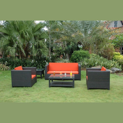 Outdoor furniture set with orange cushions on a grassy area with greenery.
