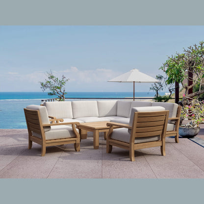 Outdoor furniture set with beige cushions and wooden frames on a patio overlooking the ocean.