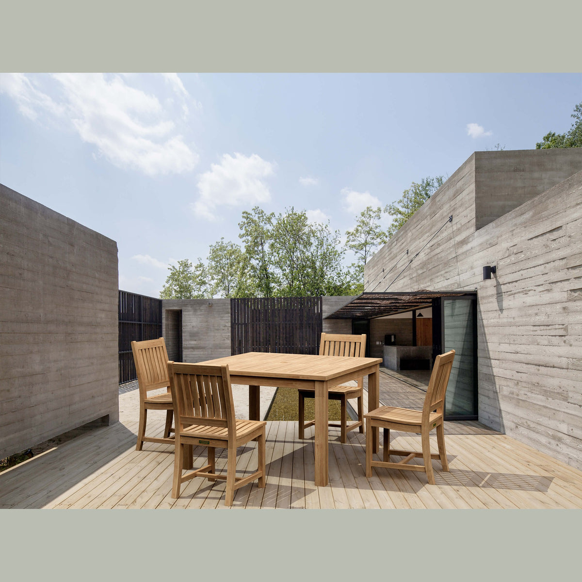 Wooden outdoor dining table with chairs in a modern architectural setting.