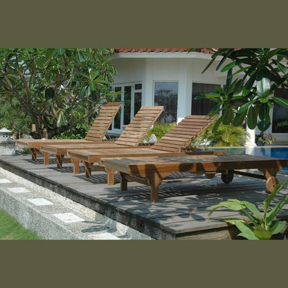 Row of wooden lounge chairs by a poolside with a building and trees in the background.