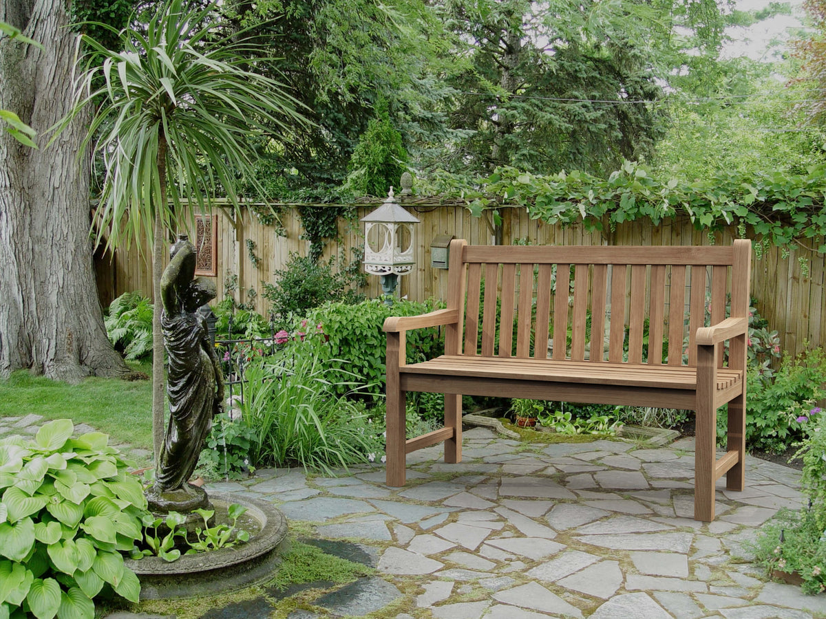 Wooden bench in a garden setting with a stone path and greenery.