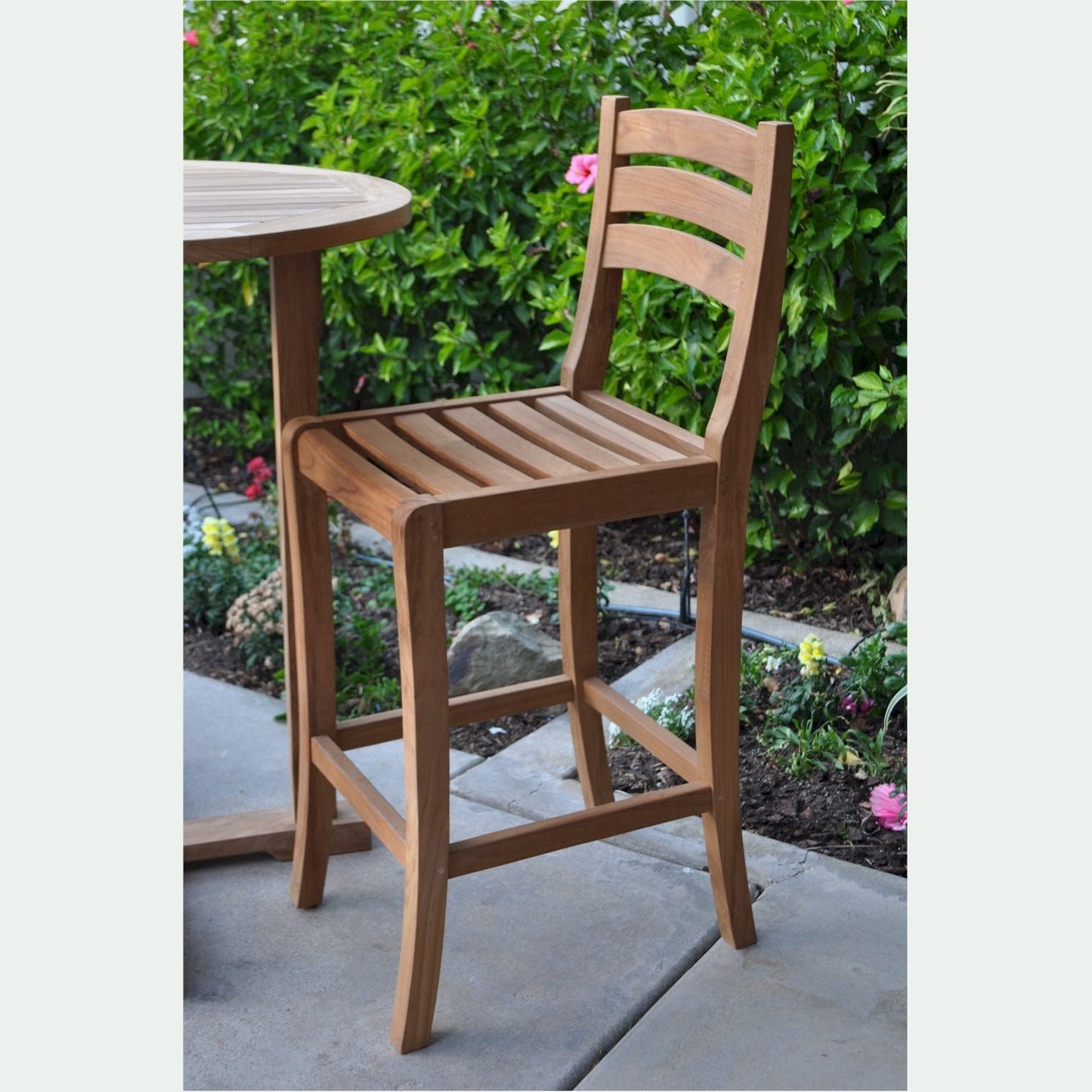 Wooden bar stool on a patio with a garden background
