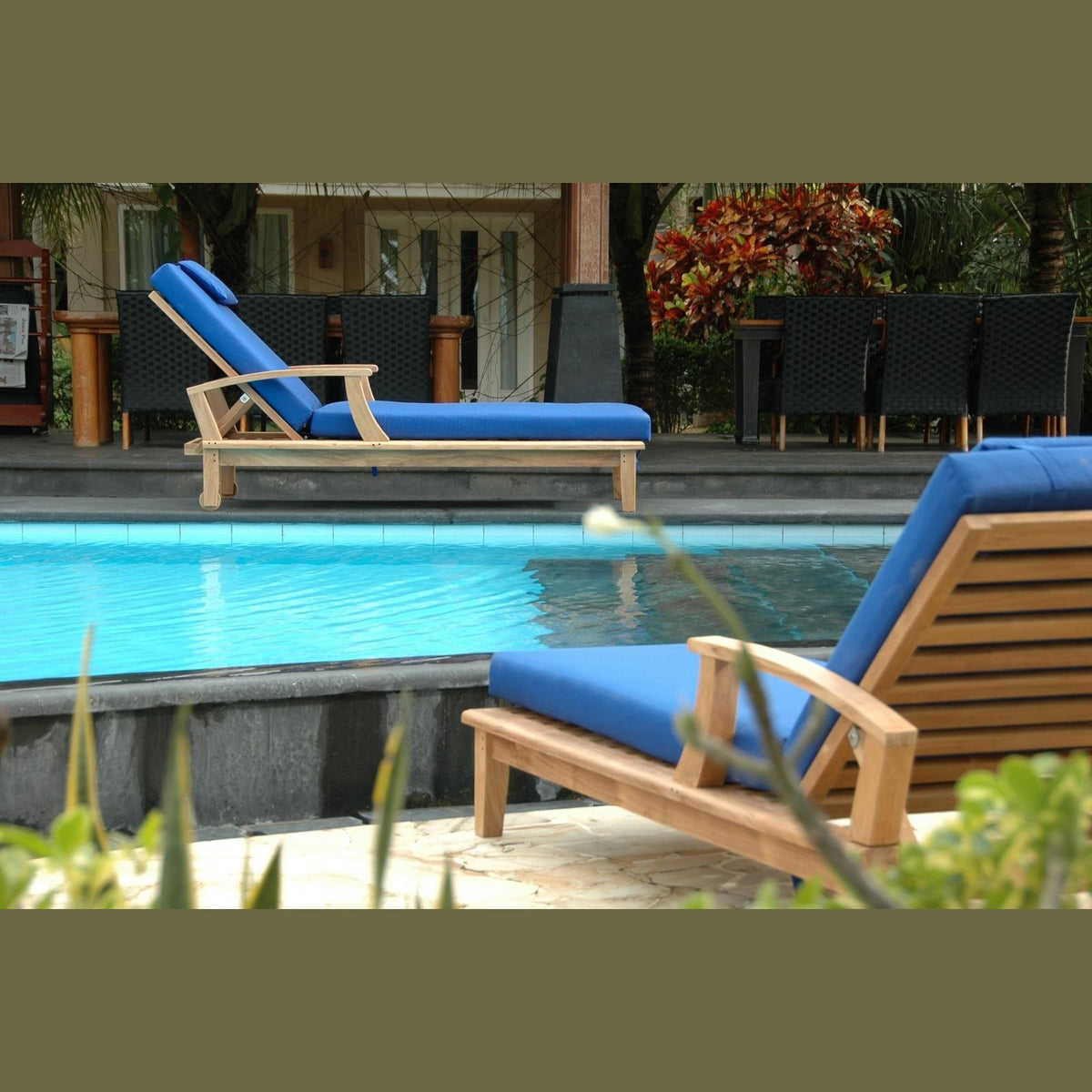 Blue lounge chairs by a pool with a tropical setting