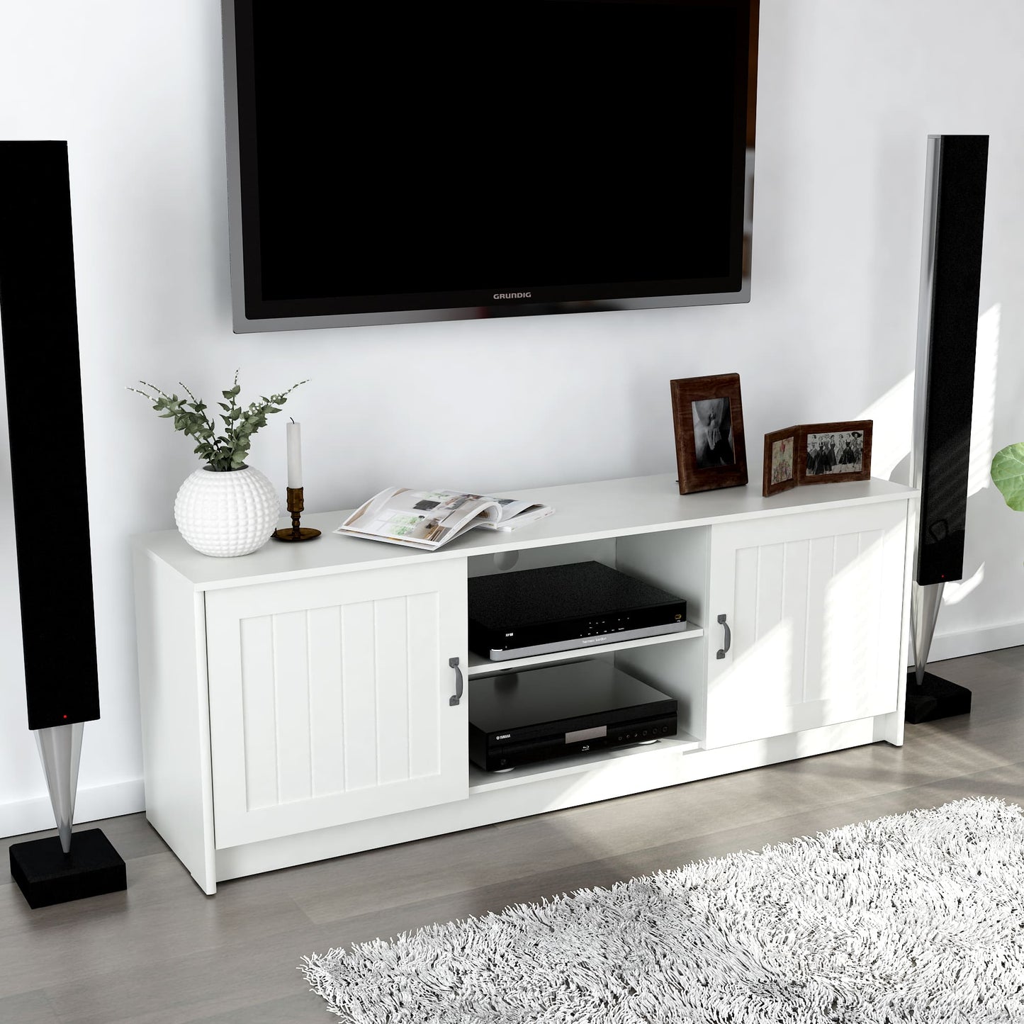 White TV stand with electronic devices, speakers, and decorative items in a room.