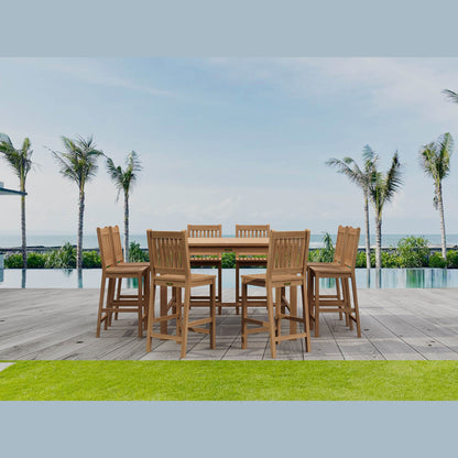 Outdoor dining set with wooden chairs and table on a patio with palm trees and pool in the background.