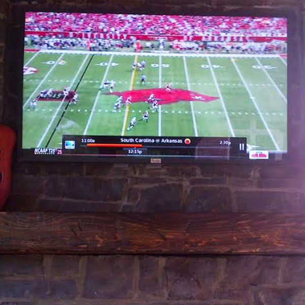 TV screen displaying a football game with a brick wall background
