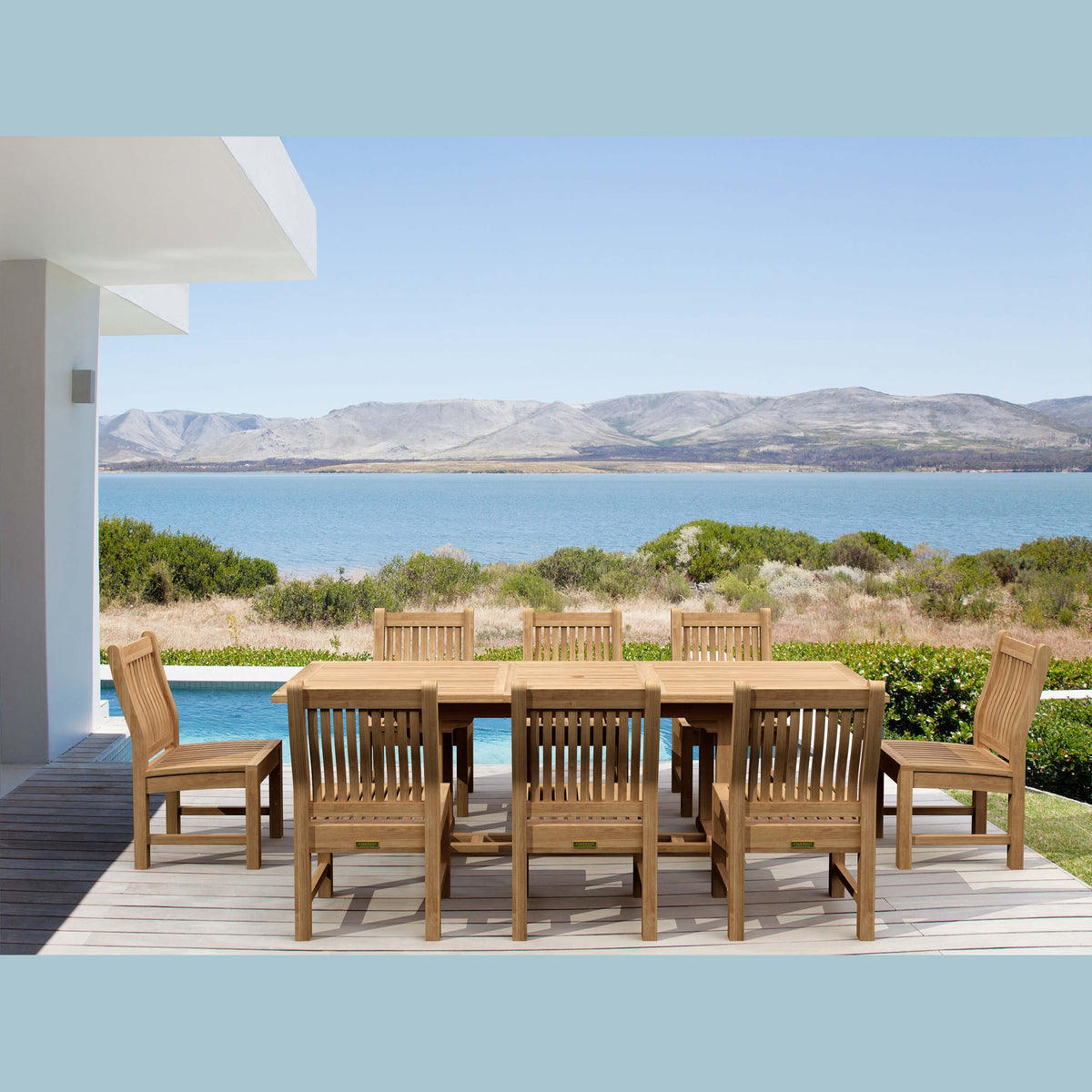 Wooden outdoor dining set with chairs on a deck overlooking a scenic view of water and mountains.