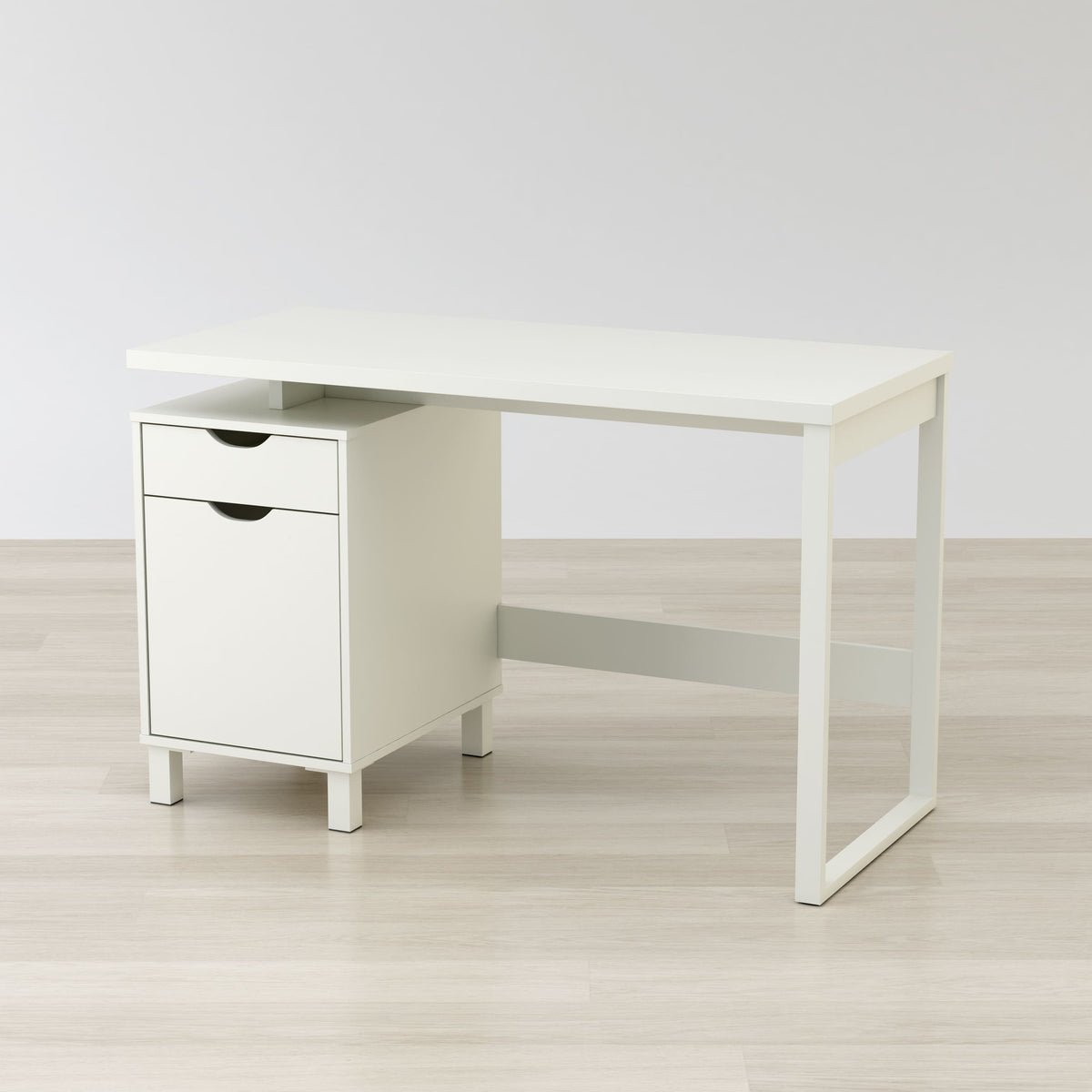 White office desk with a drawer on a light wooden floor and white wall background