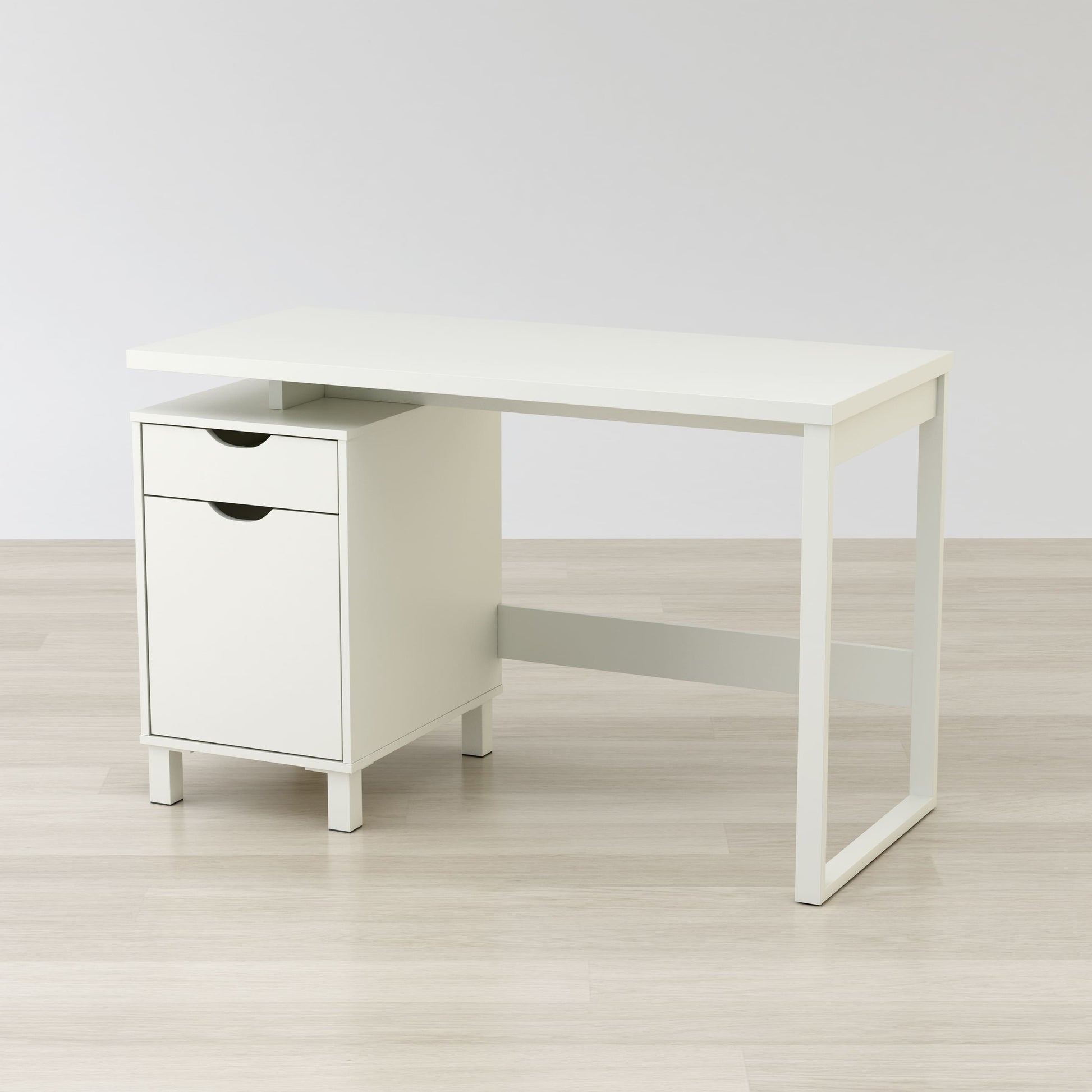 White office desk with a drawer on a light wooden floor and white wall background