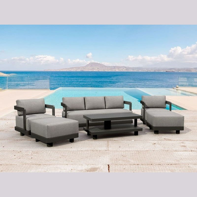 Outdoor patio furniture set with gray cushions by a pool and ocean view.