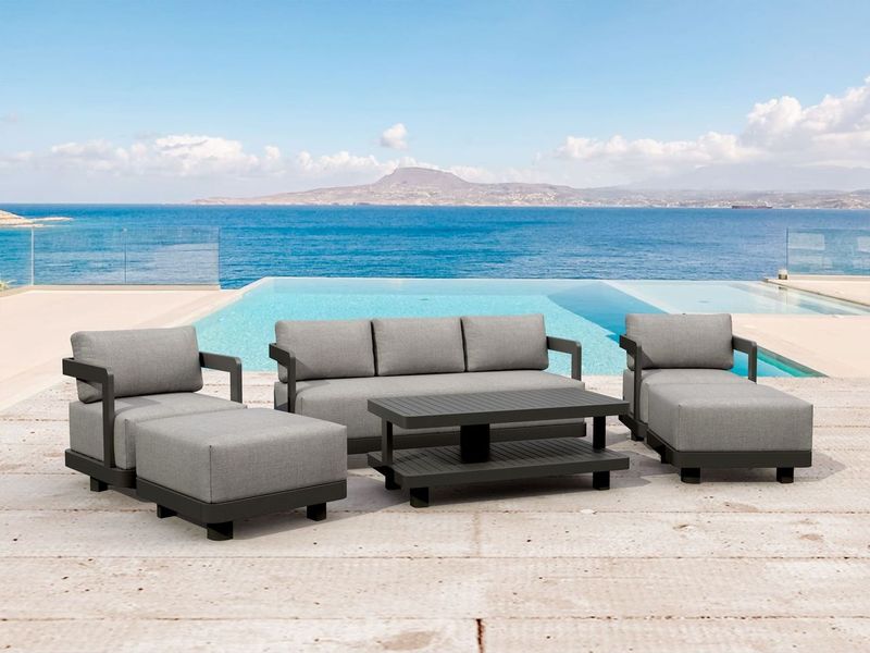 Outdoor patio furniture set with gray cushions by a pool and ocean view.
