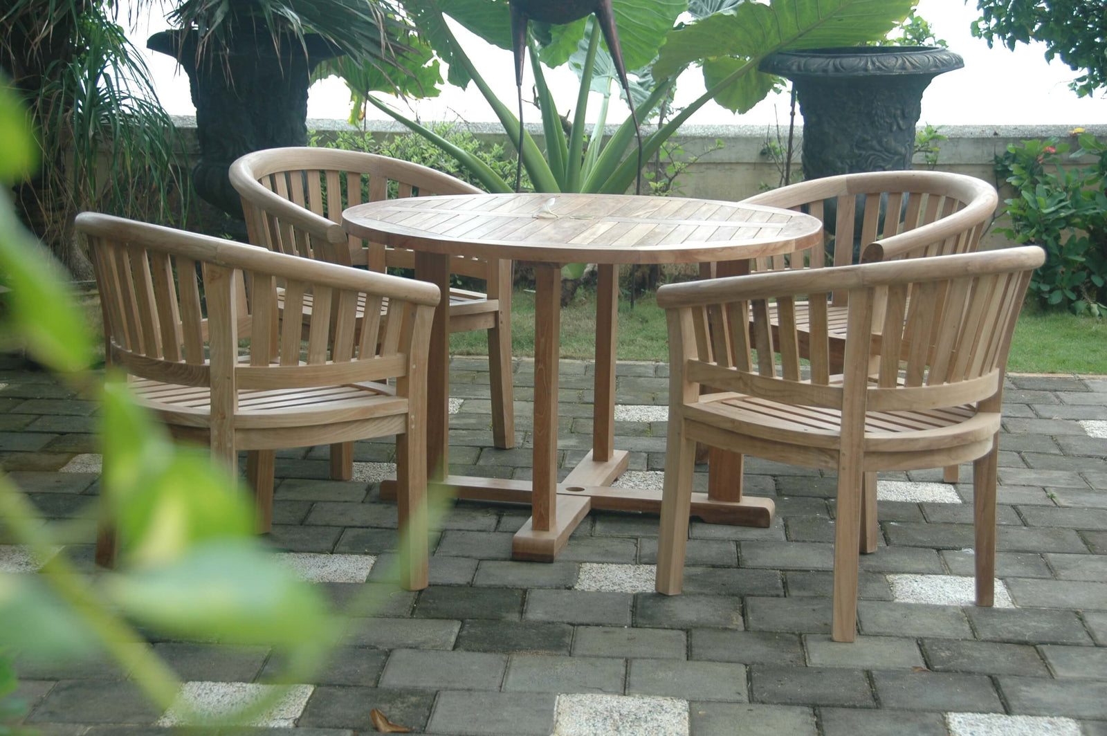 Wooden outdoor furniture set with round table and chairs on a paved patio.