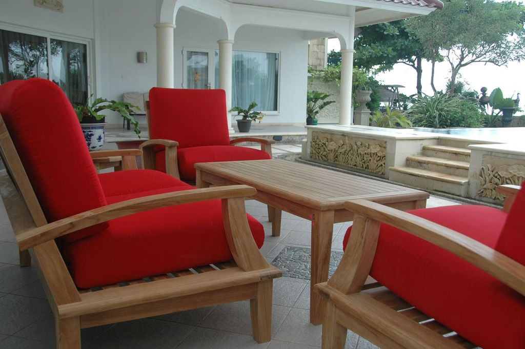 Outdoor furniture set with red cushions and wooden frames on a patio.