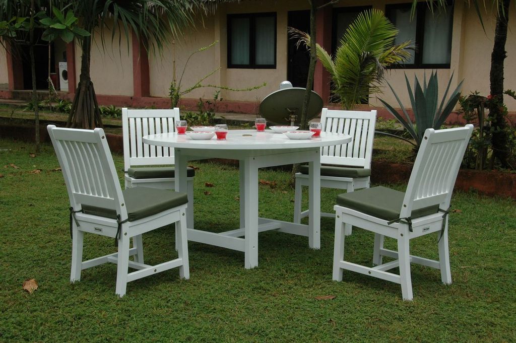 White outdoor furniture set with table and chairs on grass, house in the background