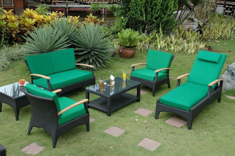 Green outdoor furniture set on a grassy area with plants in the background