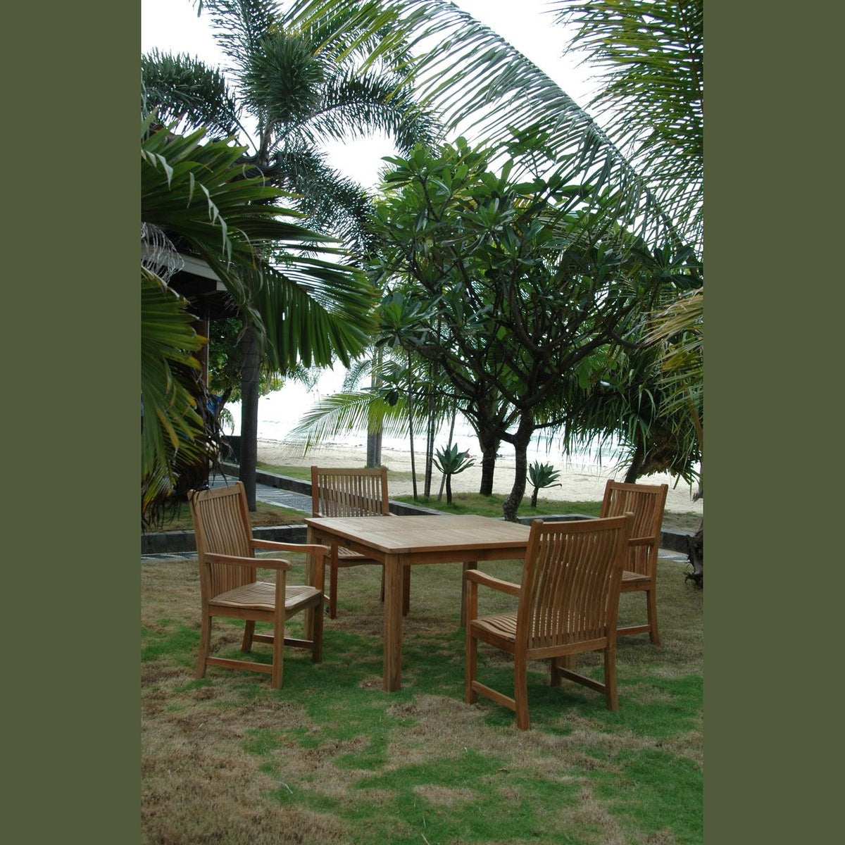 Wooden outdoor dining set with chairs on a grassy area near palm trees and a beach.