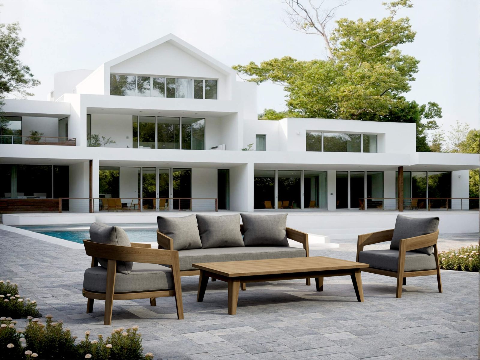 Modern outdoor furniture set on a patio in front of a white house with large windows.