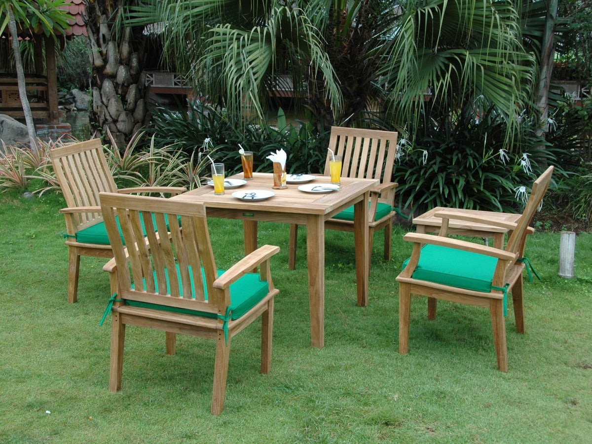 Outdoor dining set with wooden chairs and table on a grassy area with green cushions.