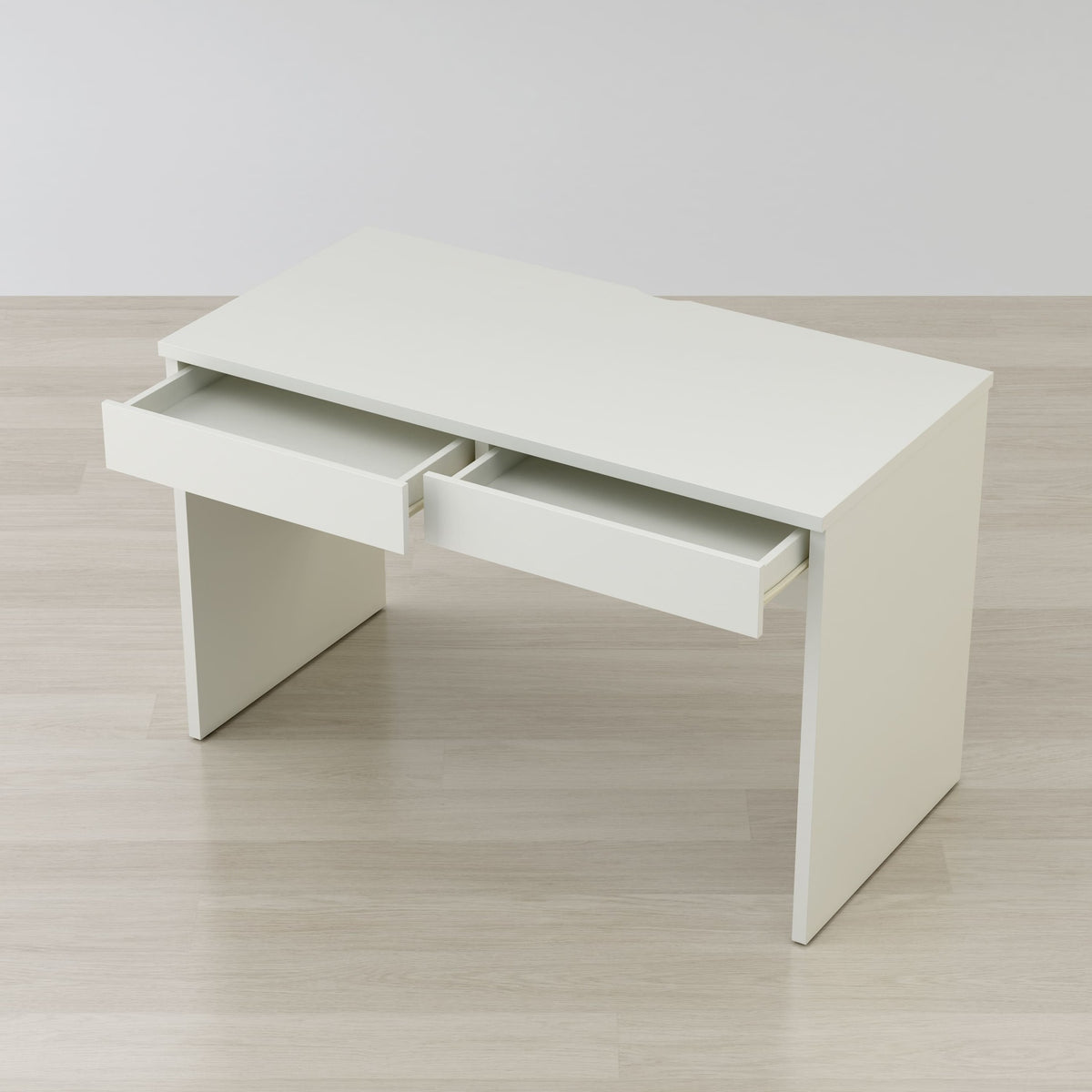 White desk with two drawers on a light wooden floor.