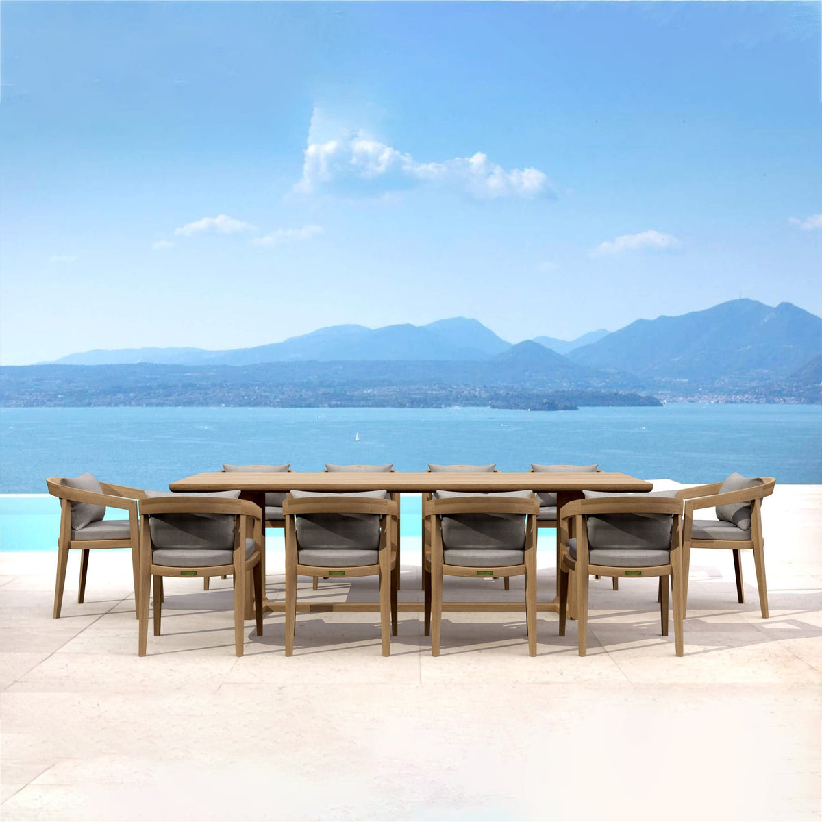 Outdoor dining set with table and chairs by a pool with a mountainous landscape in the background