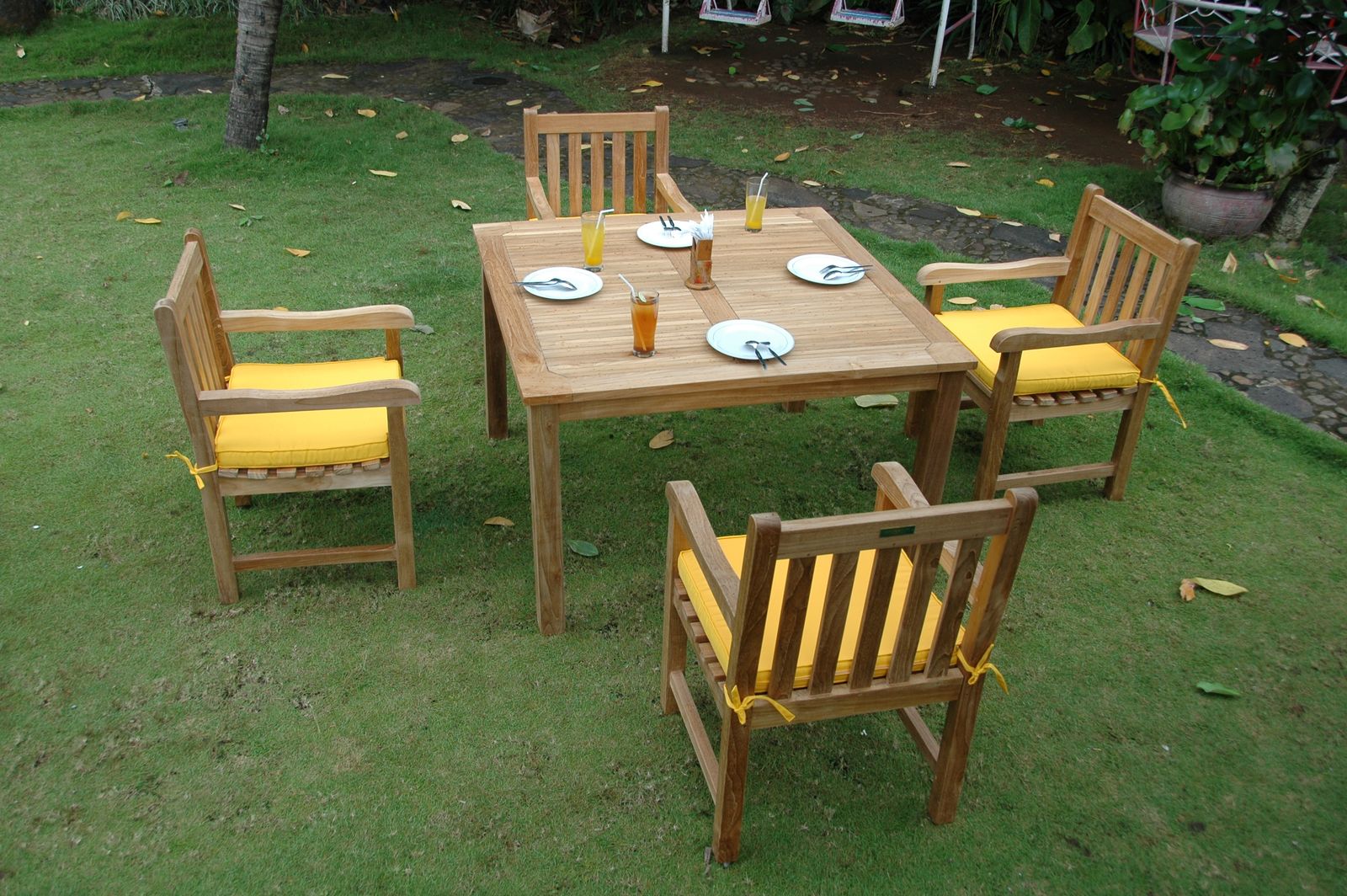Wooden outdoor table with four chairs on a grassy area