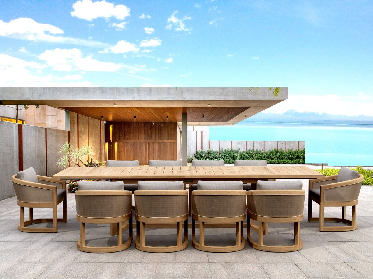 Outdoor dining set with wooden table and chairs on a patio with ocean view.