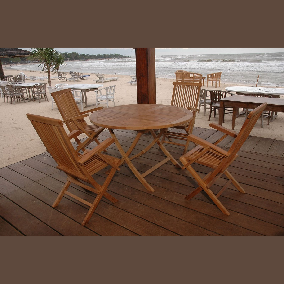 Wooden outdoor furniture set on a deck with a beach view.