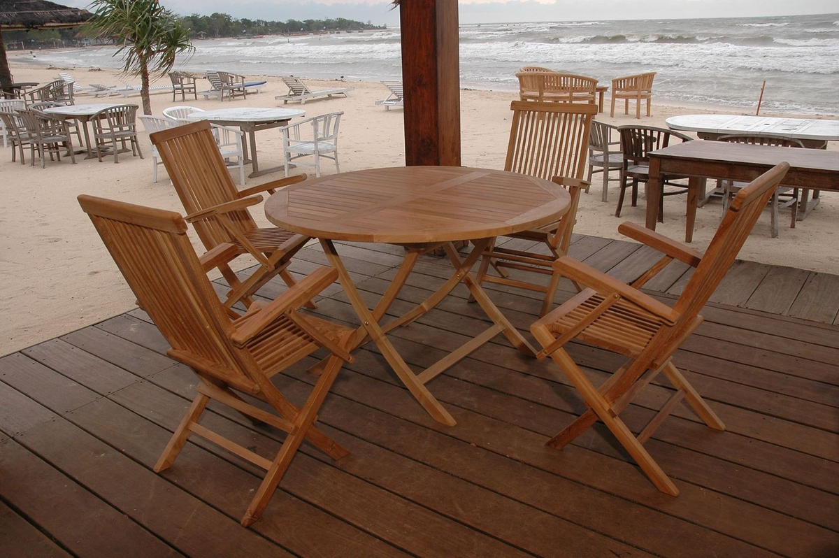 Wooden outdoor furniture set on a deck with a beach view.