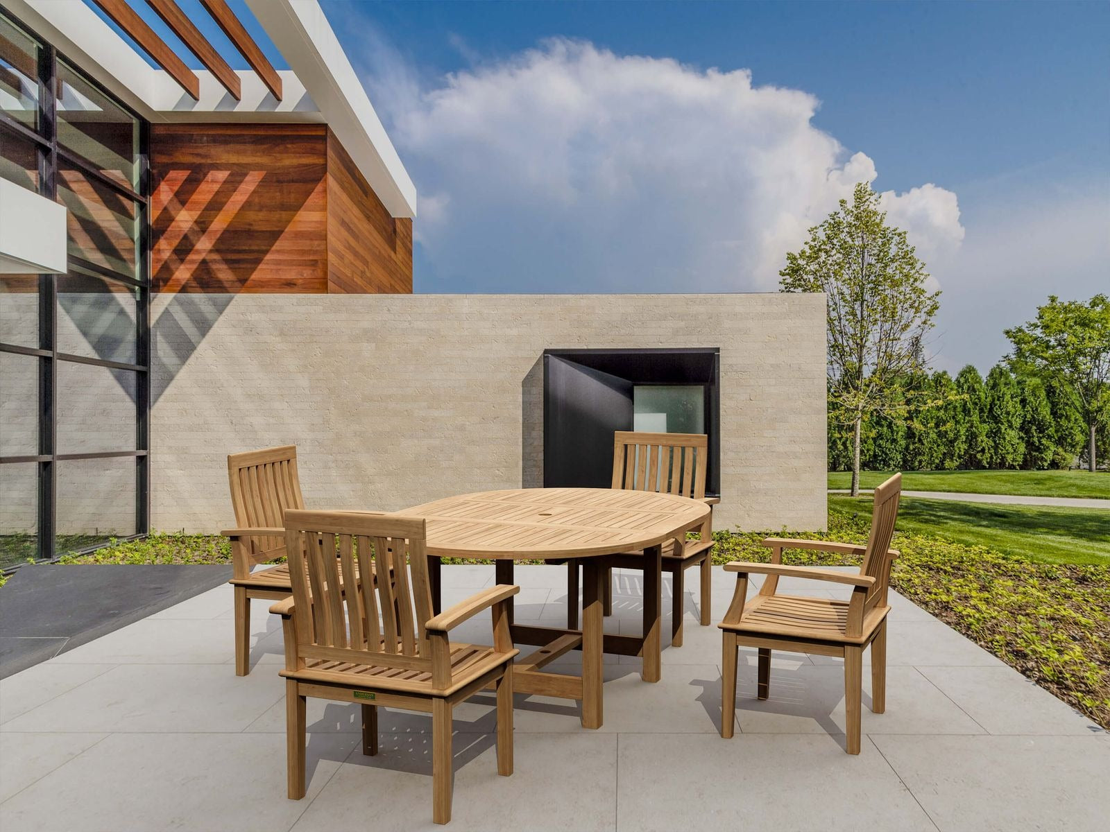 Wooden outdoor dining set on a patio with modern building and trees in the background