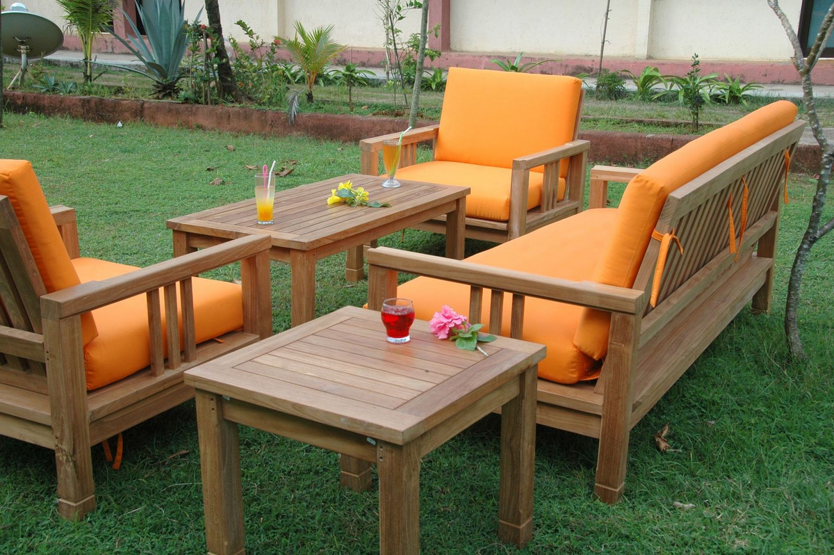 Garden furniture set with orange cushions on a grassy area