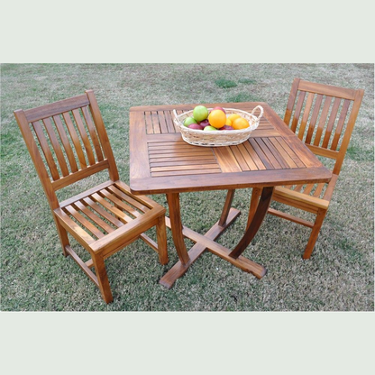 Wooden outdoor table with two chairs and a basket of fruit on a grassy background