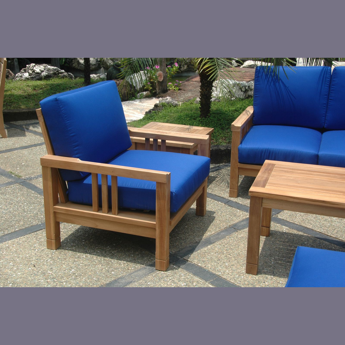 Wooden outdoor furniture set with blue cushions on a stone patio.