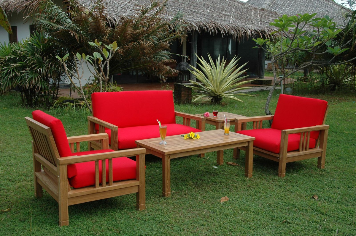 Outdoor furniture set with red cushions on a grassy area