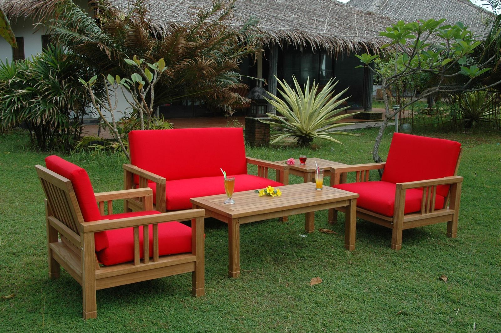 Outdoor furniture set with red cushions on a grassy area
