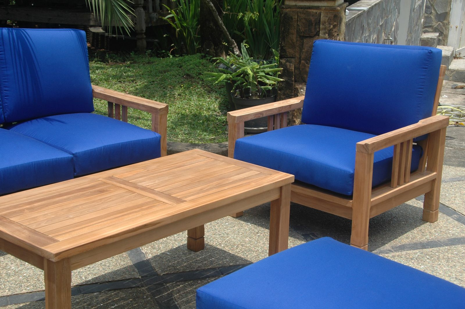 Outdoor furniture set with blue cushions and a wooden table on a patio.