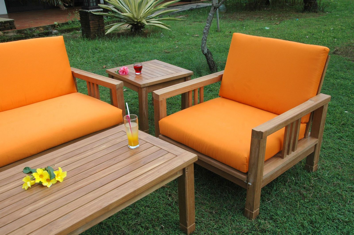 Outdoor furniture set with orange cushions on a grassy area