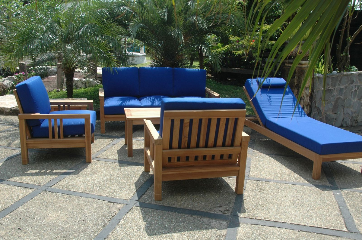 Outdoor patio furniture set with blue cushions on a stone patio.