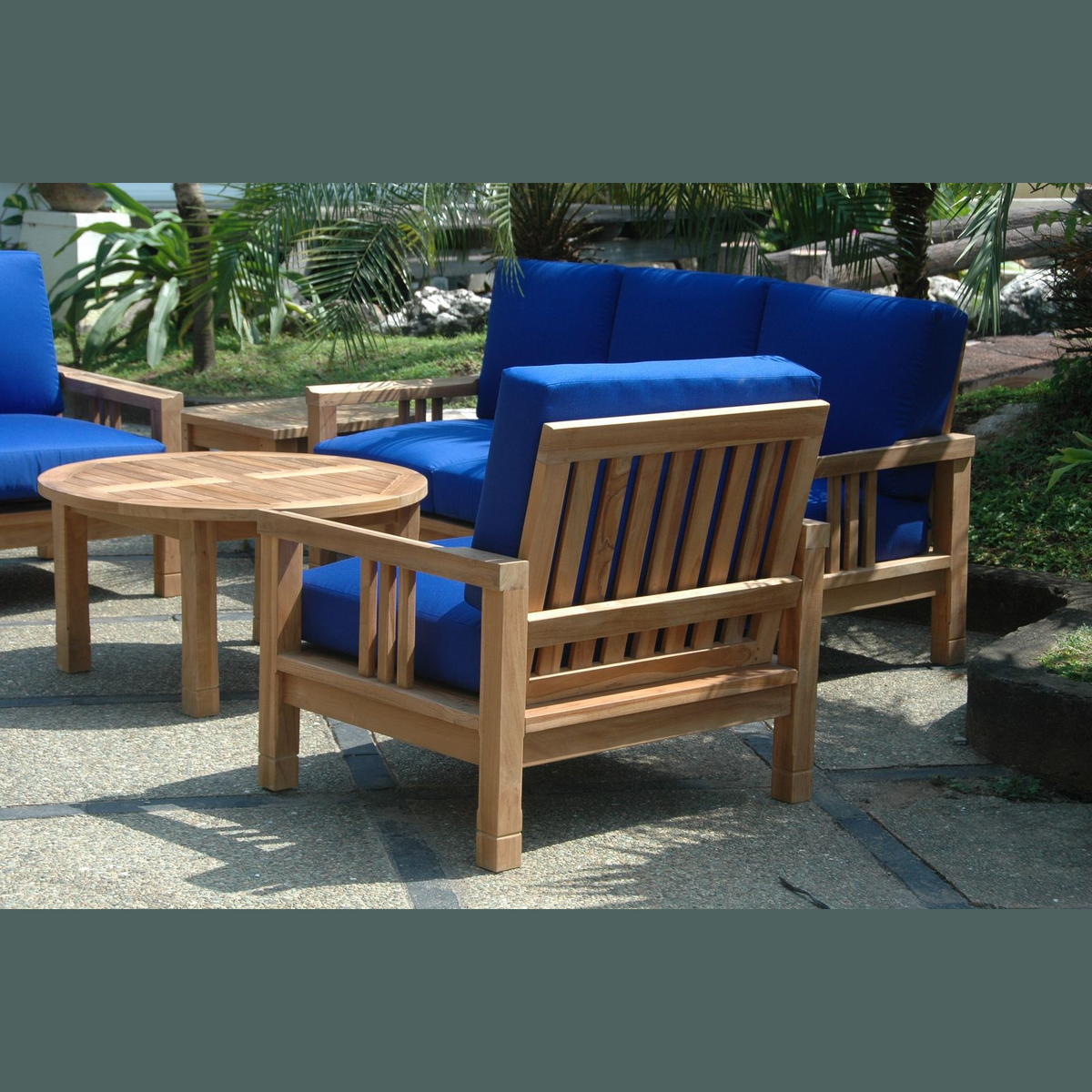 Outdoor furniture set with blue cushions and a wooden table on a patio.