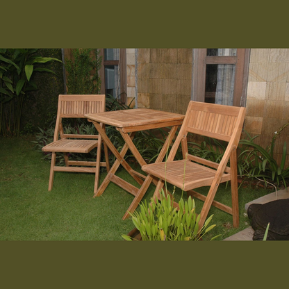 Wooden outdoor table and chairs on a grassy area with plants and a stone wall in the background.
