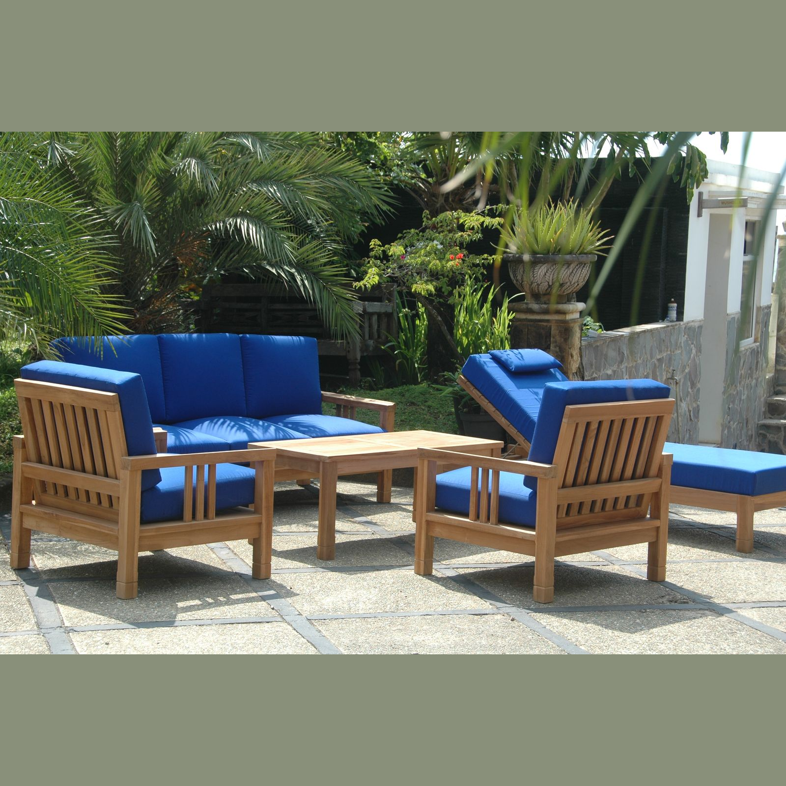 Outdoor furniture set with blue cushions and wooden frames in a garden setting.