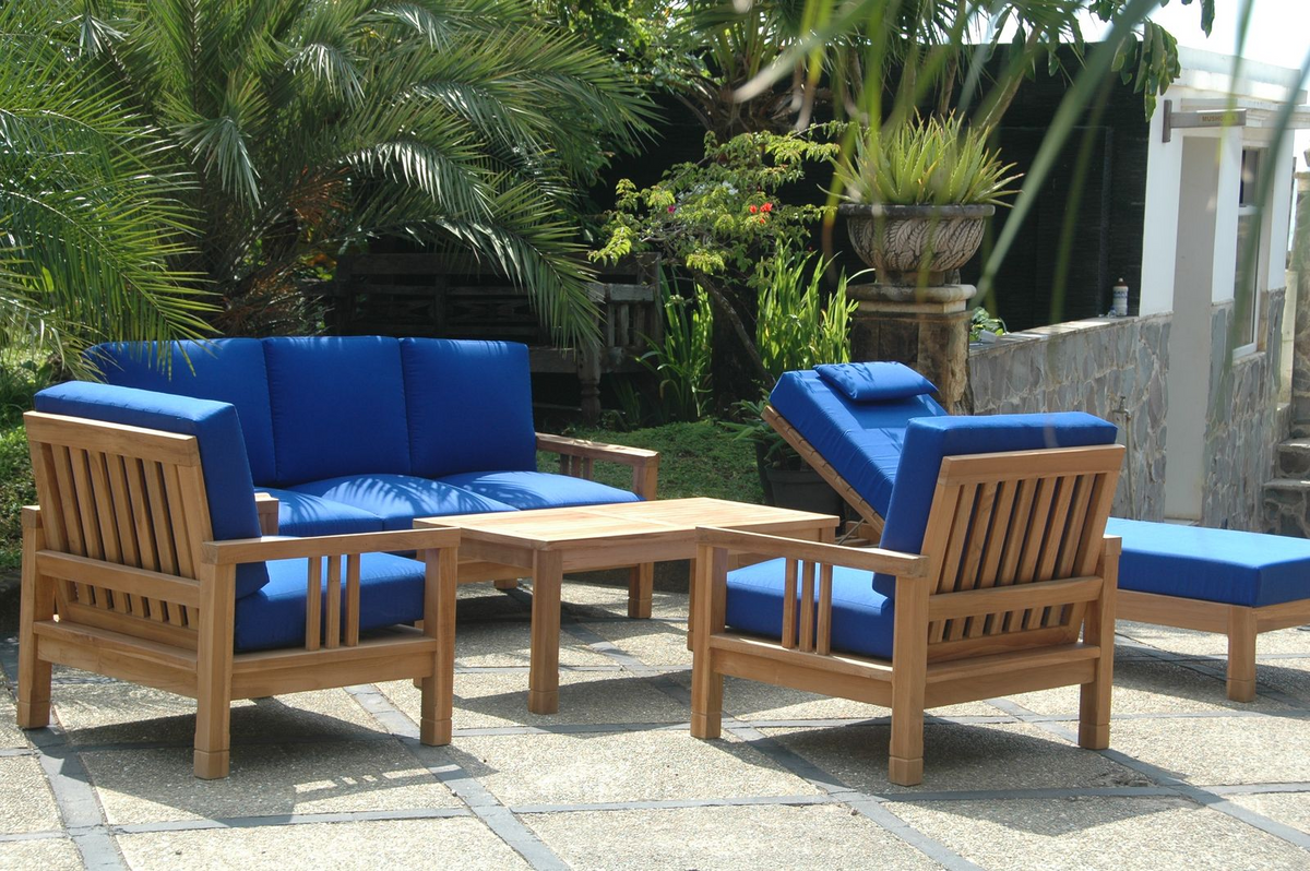 Outdoor furniture set with blue cushions and wooden frames in a garden setting.