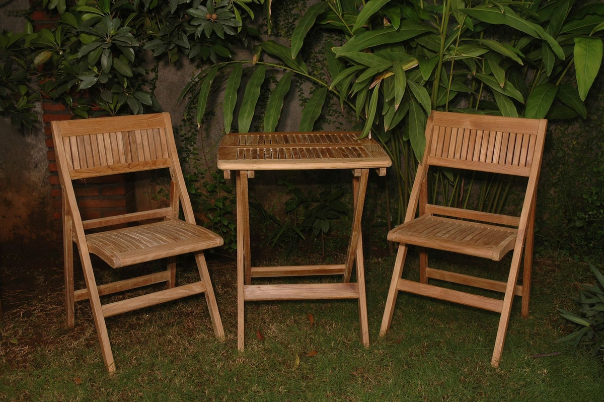 Wooden outdoor furniture set with two chairs and a small table against a green leafy background.