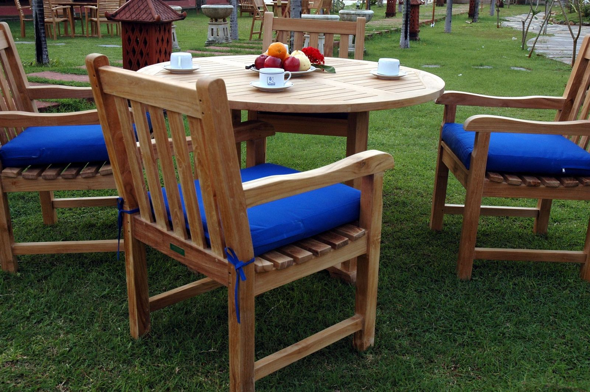 Wooden outdoor furniture set with blue cushions on a grassy area