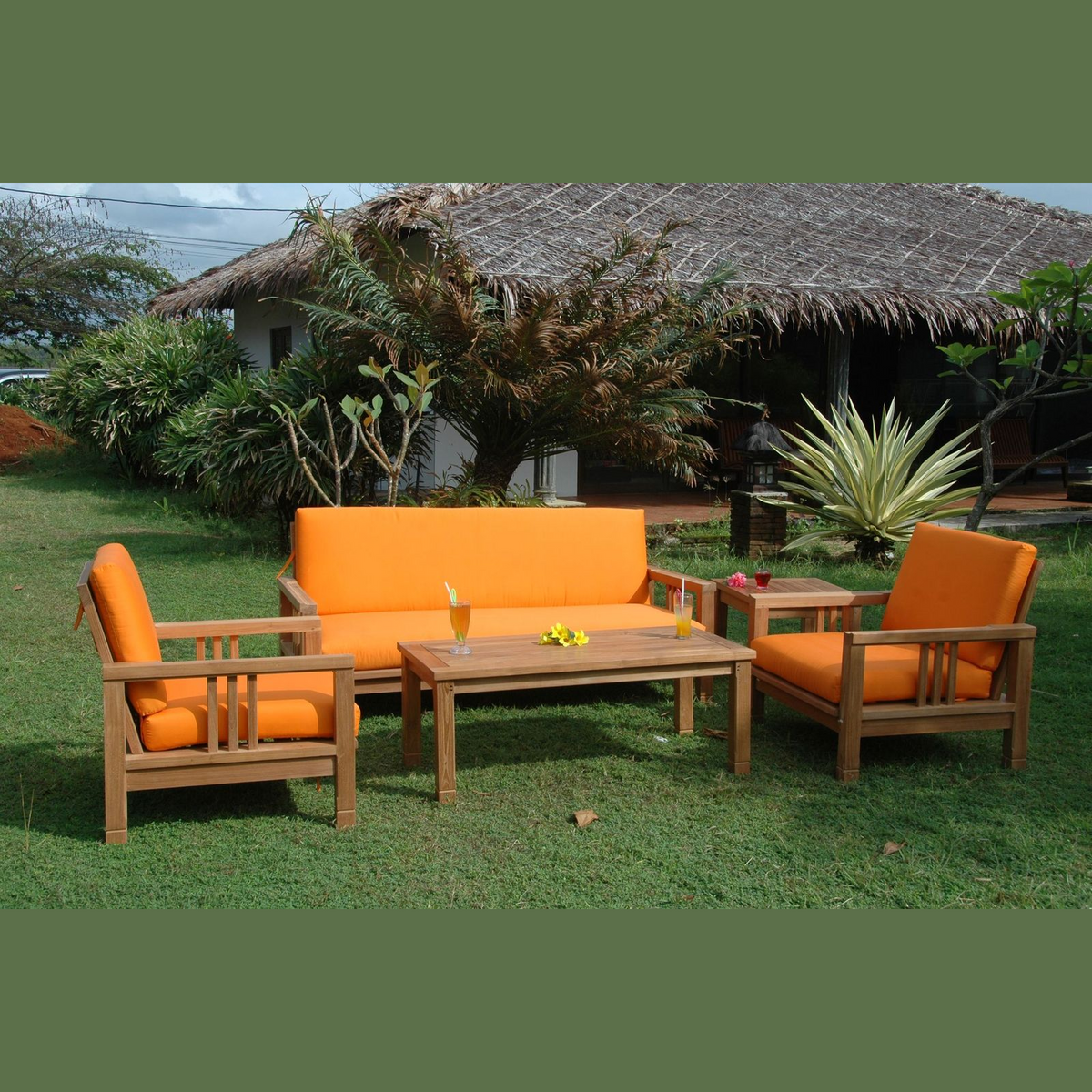 Outdoor furniture set with orange cushions on a grassy area