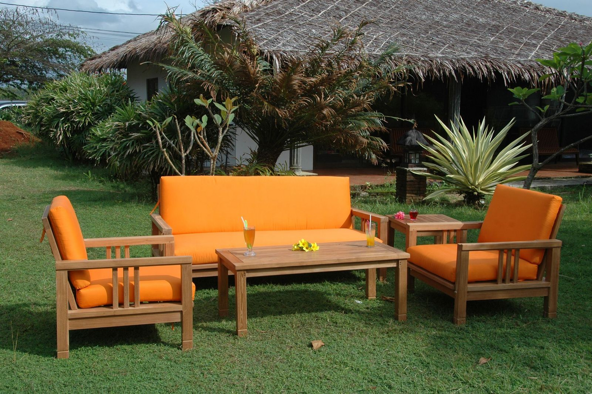 Outdoor furniture set with orange cushions on a grassy area