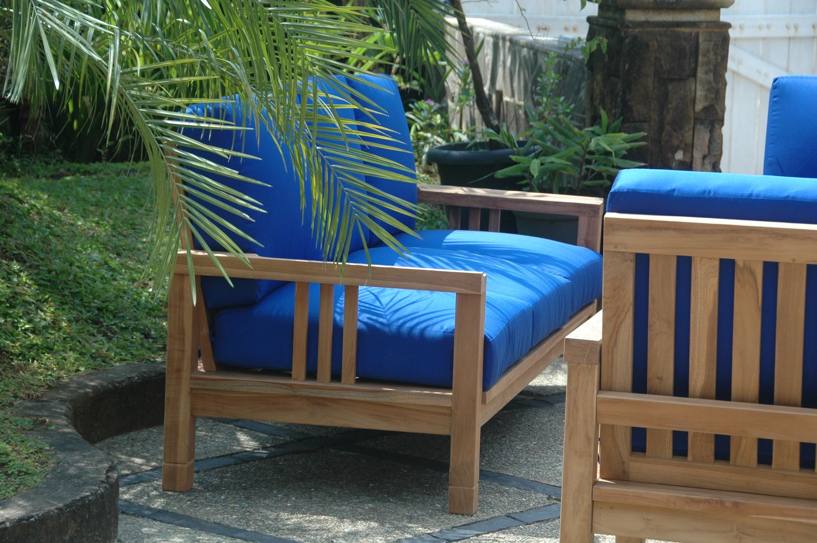 Wooden outdoor furniture with blue cushions in a garden setting
