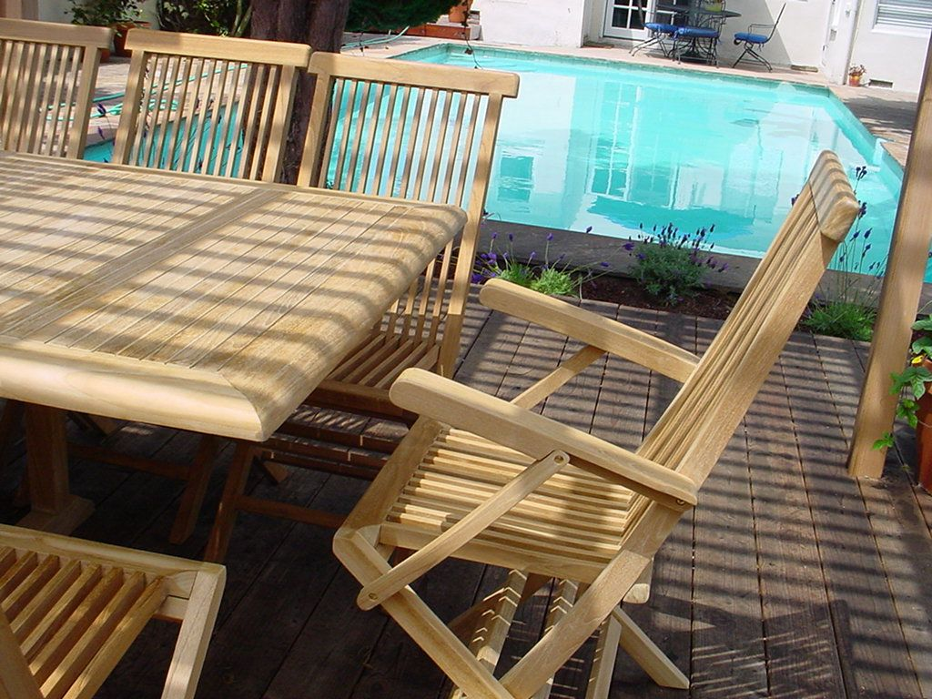 Wooden outdoor furniture set with table and chairs near a pool