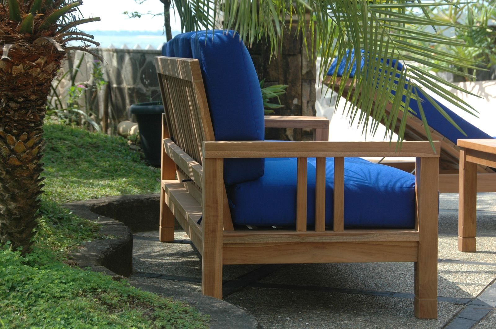 Wooden outdoor chair with blue cushions in a garden setting