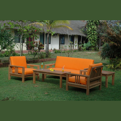 Outdoor furniture set with orange cushions on a grassy area with a building in the background.